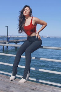a woman posing on a railing near the water