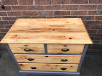 a wooden chest of drawers with grey paint