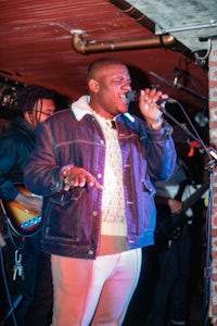 a man in a jacket singing into a microphone