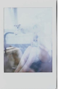 a polaroid photo of a woman sitting on a bed
