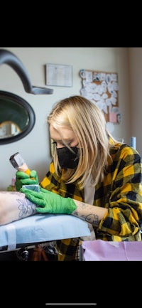 a woman is getting a tattoo on her arm