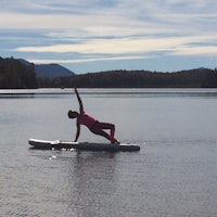 a woman doing yoga on a paddle board in a lake