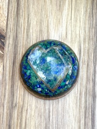 a blue and green heart shaped stone on a wooden surface