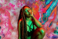 a woman with dreadlocks posing in front of a colorful background
