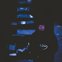 a man in a hoodie standing in a dark alley