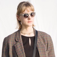 a woman wearing a plaid jacket and sunglasses