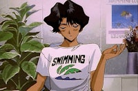 a girl in a t - shirt is sitting in front of a plant