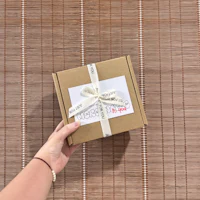 a hand holding a box with a ribbon on it