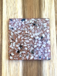 a pink and white stone coaster on a wooden table