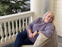 a woman sitting in a chair on a porch