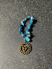 a bracelet with a blue stone and a brass charm