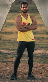 a man wearing a yellow tank top and black leggings