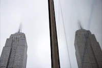 the empire state building is reflected in a window