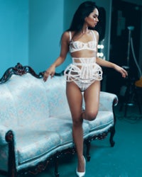 a woman in white lingerie standing on a couch