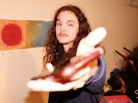 a man with long hair holding up a cell phone