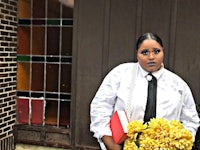 a woman in a white shirt and tie holding a bouquet of yellow flowers