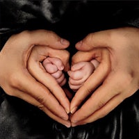 a woman's hands make a heart shape with her baby's feet