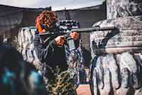 a man is holding a paintball gun in a field