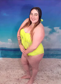 a woman in a yellow bikini posing on the beach