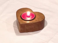a wooden heart shaped candle holder with a pink candle inside