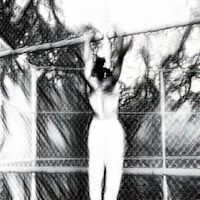 a black and white photo of a person hanging from a fence