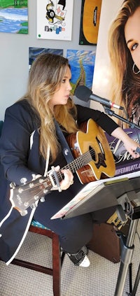 a woman playing an acoustic guitar in a recording studio