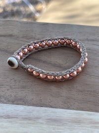 a copper beaded bracelet on a wooden table