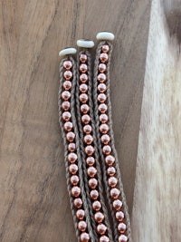 a pair of brown and copper beaded bracelets on a wooden table