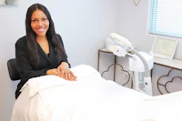 a woman smiling in front of a bed in a medical office