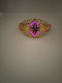 a gold and pink hair clip with a flower on it