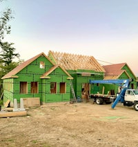 a house under construction with green framing