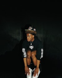 a young man crouching down in front of a dark background