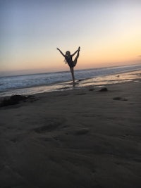 a woman doing yoga on the beach at sunset