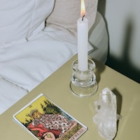 a candle and tarot card on a table next to a bed