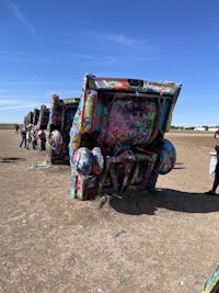 a car covered in paint is parked on a dirt road