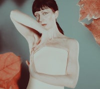 a woman in a white dress posing with leaves