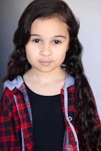 a young girl in a plaid shirt posing for a photo