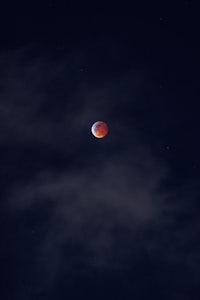 a blood moon in the sky with clouds in the background