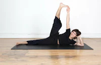 a man doing a yoga pose on a black mat