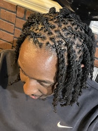 a man with dreadlocks sitting in a barber shop