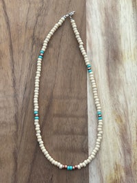 a white and turquoise beaded necklace on a wooden table