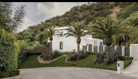a white house with palm trees and a driveway
