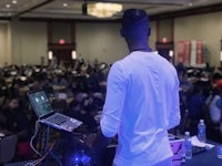 a dj standing in front of a crowd of people