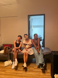 three people sitting on a bed in a room