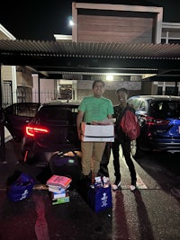 two people standing next to a car at night