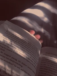 a person holding an open book in the sunlight