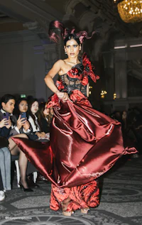 a woman in a red dress walking down the runway