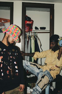 two men sitting in a closet with hats on