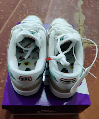 a pair of white and green sneakers on top of a purple box