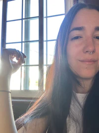 a girl with long hair sitting in front of a window